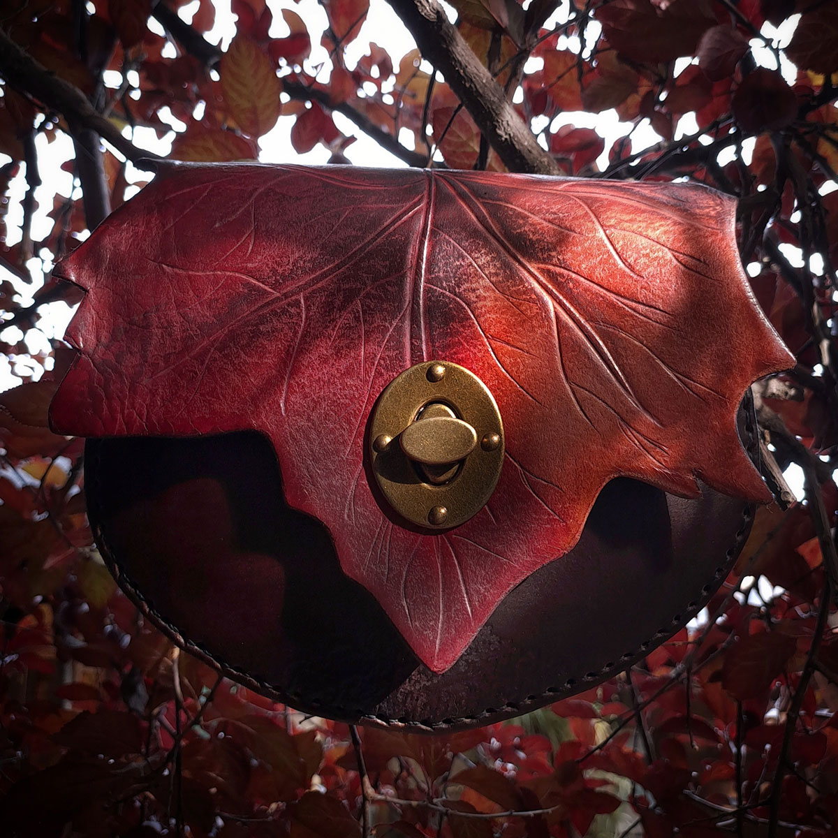 Bolso de cuero otoñal de tonos cafes y rojos con broche de cerrojo
