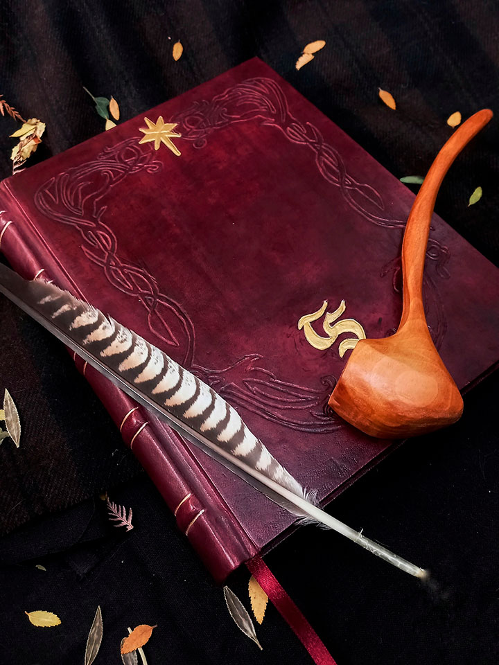 Libreta encuadernada a mano con tapas de cuero y pipa de madera con adorno de pluma de ave